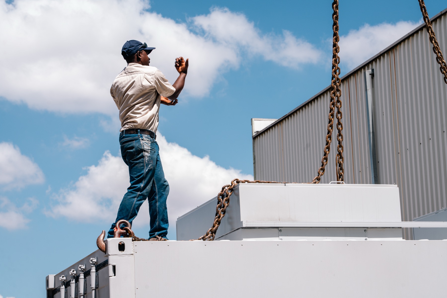 Rigger guiding a containerised energy unit into place on site