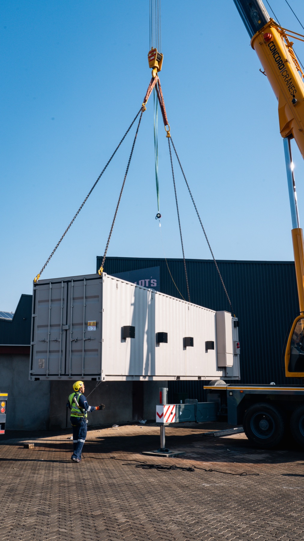 Container being craned into place with a worker directing, Energy Capital Medi Clinic