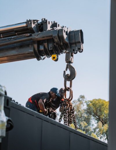 Engineers attaching a crane hook to a container