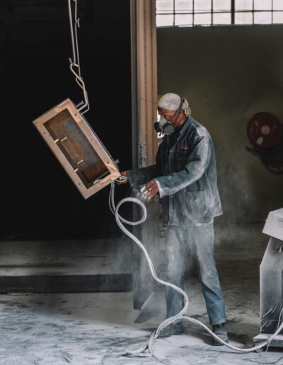 Side view of a worker painting a metal frame
