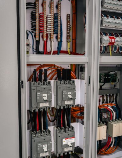 Side-view of industrial electrical cabinet with open doors, showing internals.