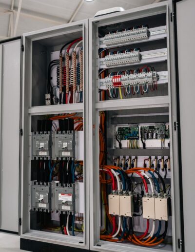 Side view of industrial electrical cabinet with open doors, showing internals.