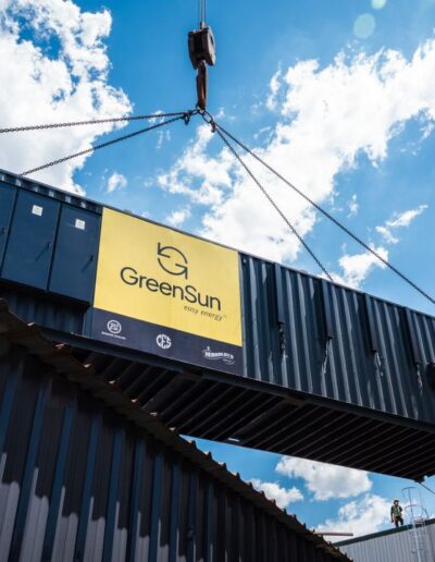 A crane moving a GreenSun branded container